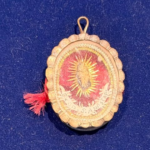 The holy relic of Saint Anastasia in its small oval gold reliquary, on a blue cloth, with a red tassel.
