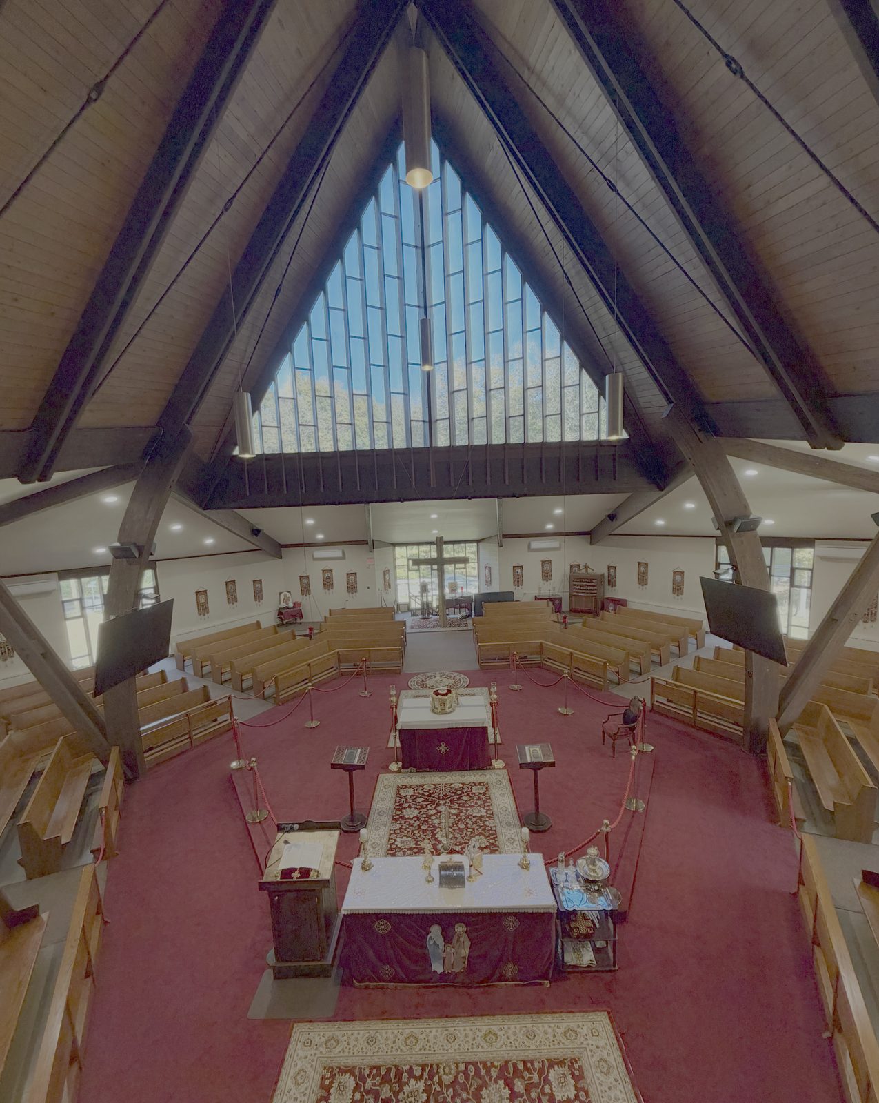 The tall triangular window and wooden roof beams above the altar, seen from the balcony