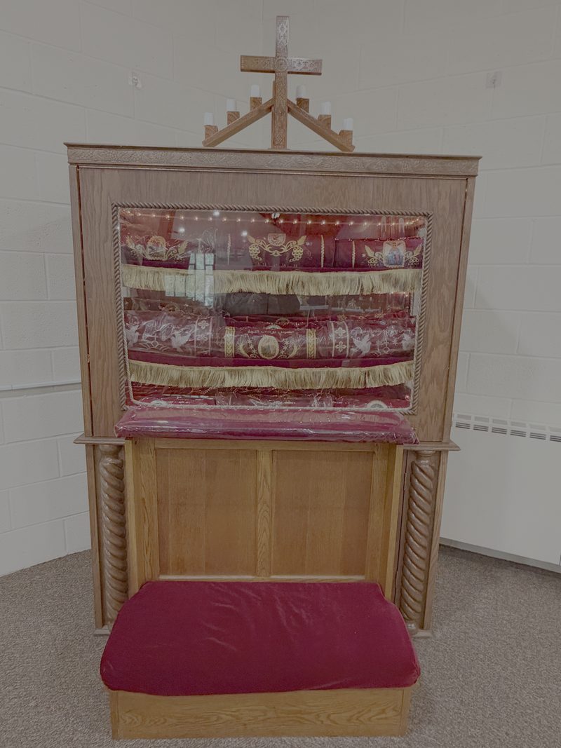The wooden cabinet where the relics are kept, with a cross and candles on top