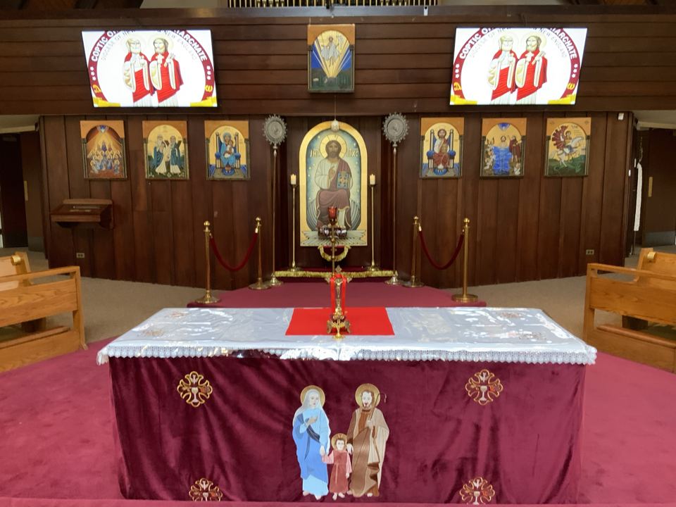 The altar in the sanctuary, covered with an embroidered cloth, with the icon of Christ behind it.