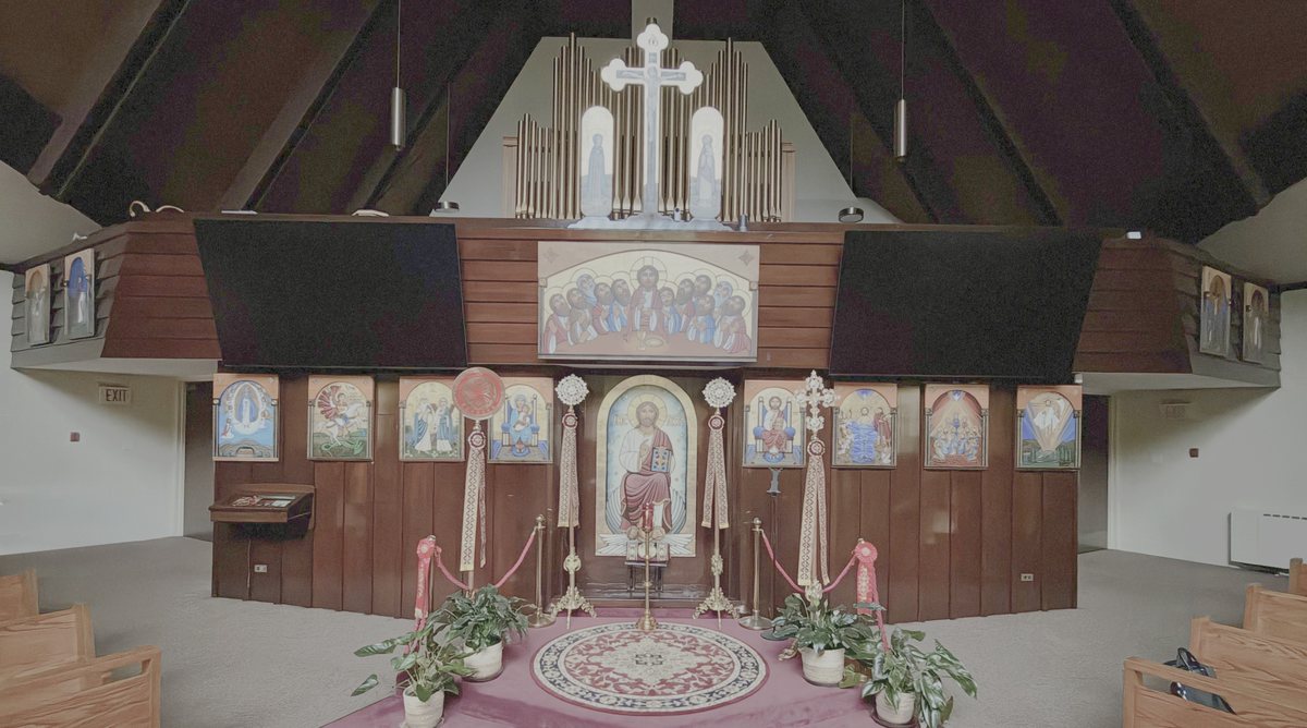 The wall of icons behind the altar: Christ enthroned at the center, with the cross and the organ pipes above.